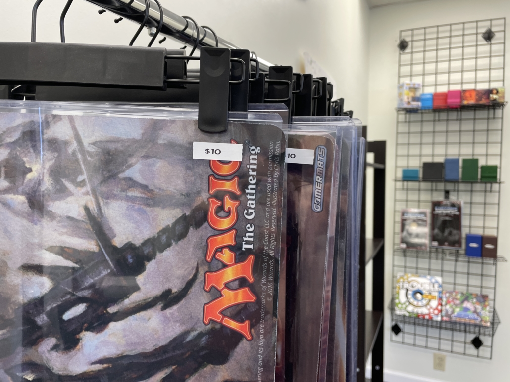 Hanging Magic playmats in the foreground with wall shelves and product in the background.